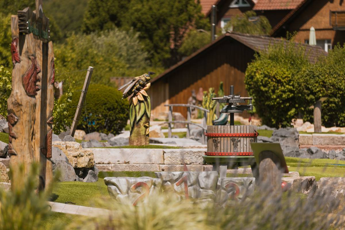 Weintrotte und geschnitzte Holzfiguren auf dem Erlebnis-Minigolfplatz im Natur-Resort Hessenmühle